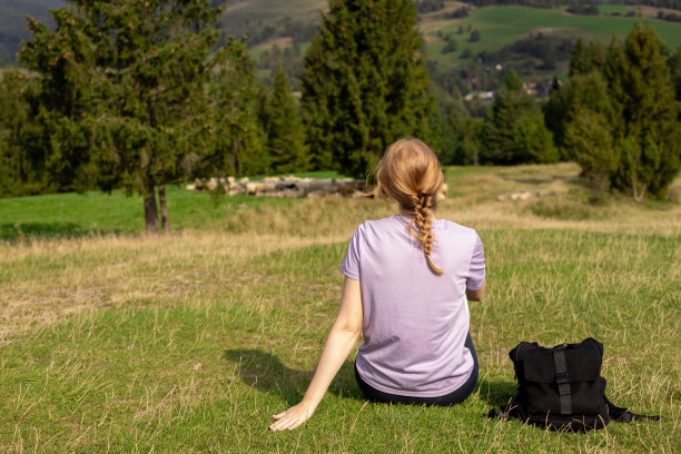 徒步旅行后，穿着运动服休息的妇女的后视图。旅行和积极的生活方式理念。30多岁的女孩在山顶欣赏山谷美景，户外活动图片下载