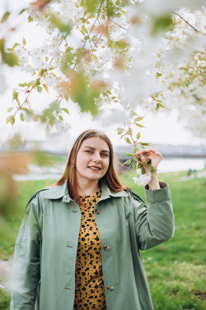 年轻女子在春暖花开的花园里享受香味。春姑娘照片。温柔的女人在樱花背景的肖像。在盛开的花园里庆祝花见。图片下载