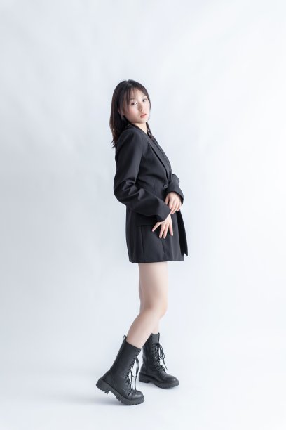 身穿黑色西装和靴子的亚洲女子在白色背景上摆姿势图片下载