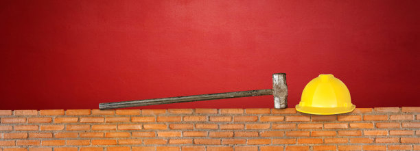 红砖墙红水泥背景上的帽子和锤子图片下载