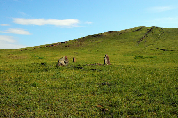 夏季大草原上一座高山脚下一座古代墓葬的石栅栏全景照片。图片下载