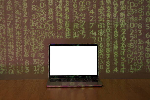笔记本电脑与空间为您的信息在木桌上二进制代码背景在黑暗的房间。图片下载