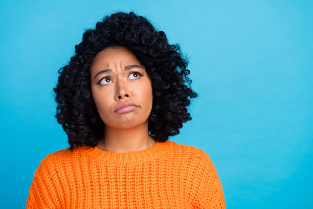 照片肖像迷人的年轻女子看起来不开心空穿时髦的针织衫橙色的衣服孤立在蓝色的背景图片下载