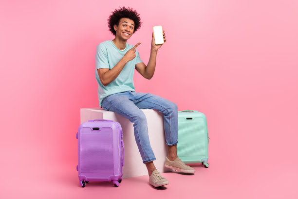 有吸引力的年轻男子的全身照片，手指点设备屏幕旅行者穿着时髦的蓝色衣服孤立在粉红色的背景图片下载