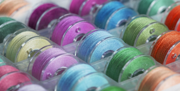 在一个收纳盒里，有颜色鲜艳的线的缝纫机用塑料线轴。图片下载