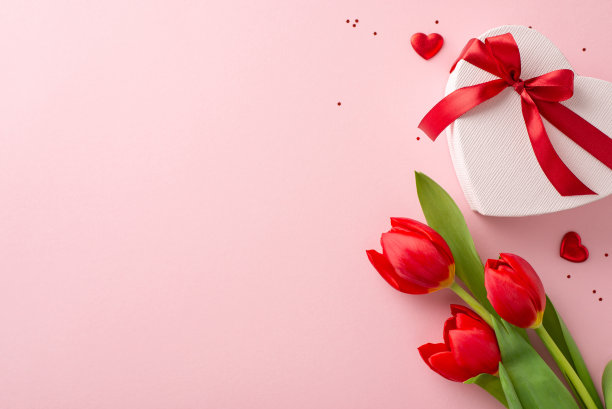 完美的淑女式庆典设计。一个心形包装的俯视图，在淡粉色的画布上有丝带、闪光、心形剪纸和新鲜的郁金香花，上面有文字或广告的空间图片下载