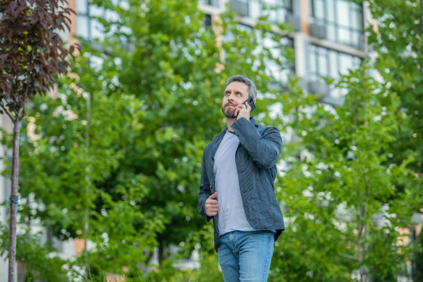男子在智能手机上打电话和谈话的照片视图。男子在户外用智能手机打电话。图片下载