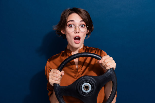 震惊的女士穿着时髦的衣服开着汽车速度试驾旅行的照片，在深蓝色的背景上孤立的道路图片下载