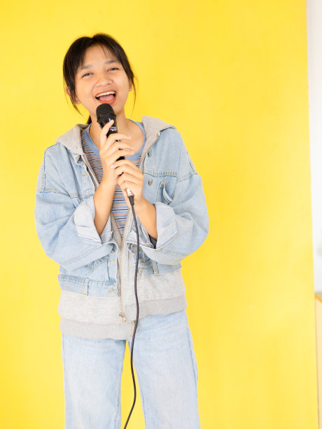 年轻的女孩在黄色的背景上欢快地唱歌跳舞。图片下载