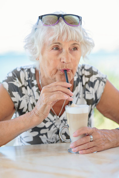 迷人的老女人坐在夏日的户外咖啡馆里图片下载