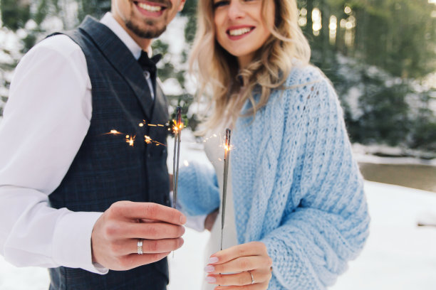 冬天，新郎穿着背心，新娘裹着蓝色毯子，在街上拿着燃烧的烟花和烟花图片下载