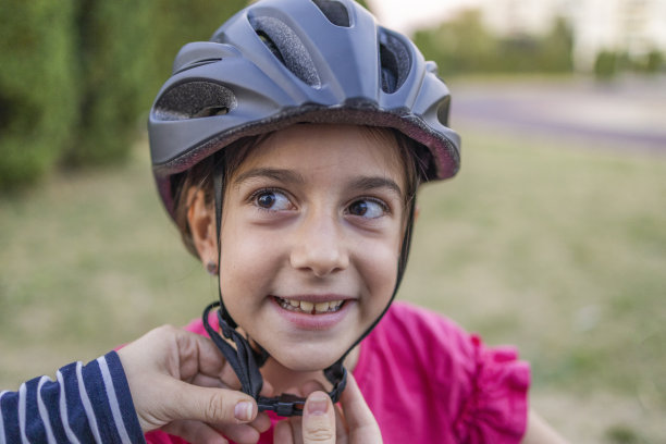 妈妈给女儿系头盔的特写照片。孩子们的安全图片下载