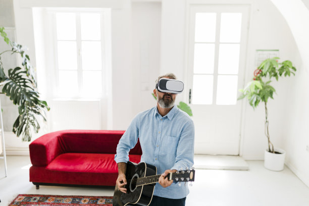 老人戴着虚拟现实眼镜在弹原声吉他图片下载