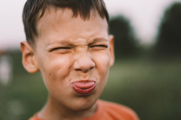 一个穿着橙色t恤的有趣男孩在日落时分在户外操场上玩耍的照片。图片下载