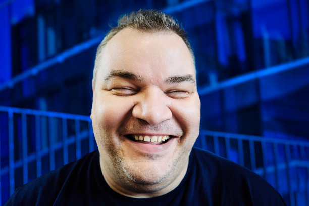 40多岁的大块头白人男人露齿微笑，蓝色背景的特写肖像，广角镜头失真，真正的数码照片。图片下载