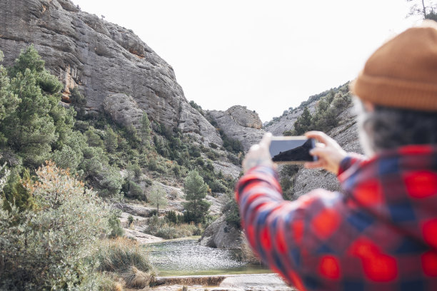 一个戴着帽子的女人拍了一张山和河的照片图片下载