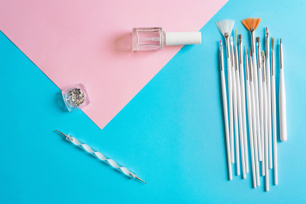 美甲工具的排列:各种风格的刷子，闪光的闪光，透明的清漆，在充满活力的蓝粉色背景下。图片下载