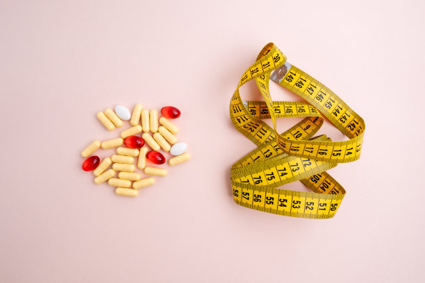 维生素片，彩色背景上带卷尺的药片。计算卡路里和减肥。健康饮食理念-计算每日食物摄入量图片下载