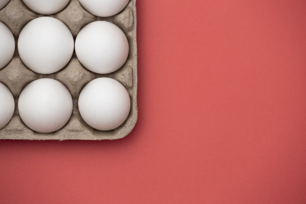 白色的鸡蛋在盒子上的特写在红色的背景-股票照片图片下载
