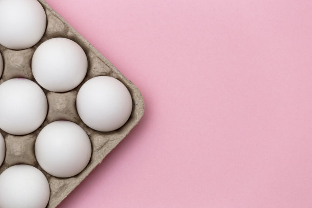 白色的鸡蛋在盒子上的特写粉红色的背景-股票照片图片下载