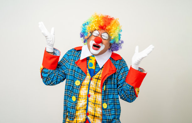小丑先生。悲伤的脸的肖像小丑在彩色制服站哭感觉悲伤的情绪。在孤立的背景上以各种姿势表达男性笨蛋。图片下载