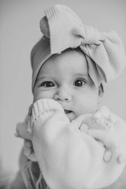 可爱的女婴肖像与蝴蝶结在头发孤立的白色背景。可爱的婴儿，6个月大的特写。漂亮的小女孩，大眼睛，头上戴着蝴蝶结发带。黑白照片图片下载