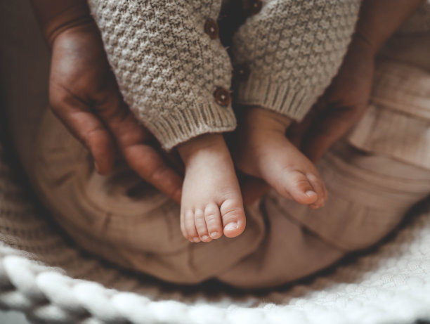 新生儿在妈妈手中的小双腿，母性和关爱的概念图片下载