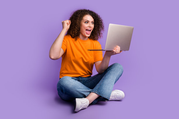 照片的快乐快乐迷人的女人穿着时尚的衣服坐在地板上看视频支持团队孤立的紫色背景图片下载