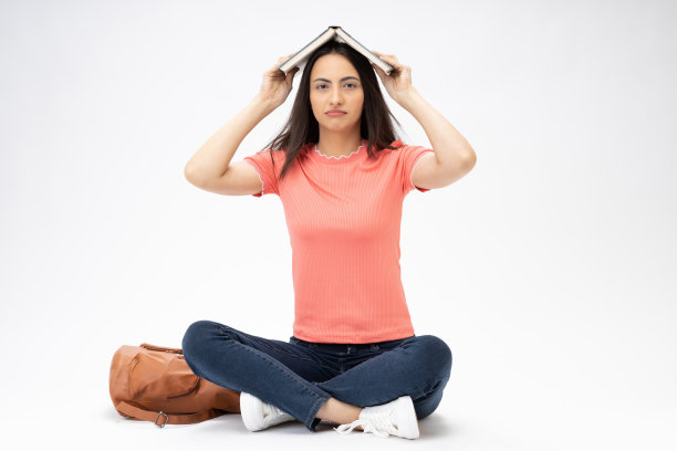 全身尺寸的年轻女孩读书坐在地板上穿着牛仔裤牛仔粉t恤鞋孤立在白色背景股票照片图片下载