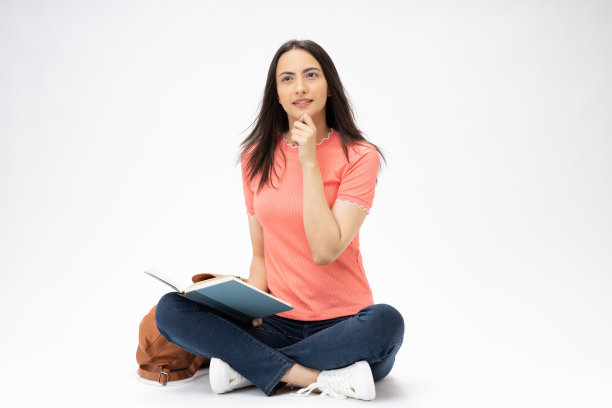 全身尺寸的年轻女孩读书坐在地板上穿着牛仔裤牛仔粉t恤鞋孤立在白色背景股票照片图片下载