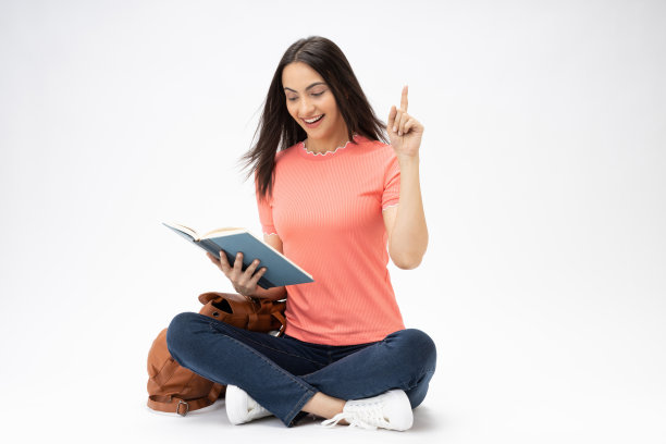 全身尺寸的年轻女孩读书坐在地板上穿着牛仔裤牛仔粉t恤鞋孤立在白色背景股票照片图片下载