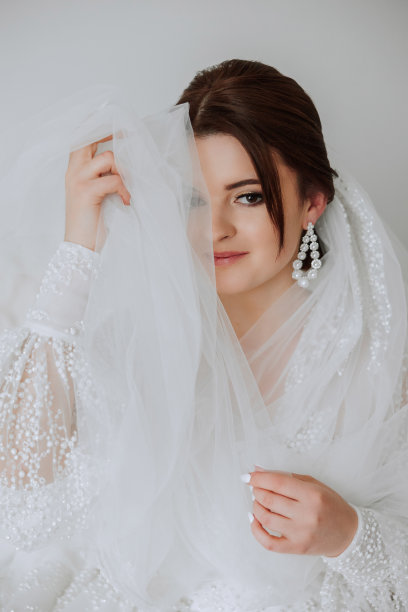 婚礼的早晨，一位美丽的新娘穿着优雅的婚纱，一头黑发，化着迷人的妆，在房间里拍摄的时尚照片。新娘正在为婚礼做准备图片下载