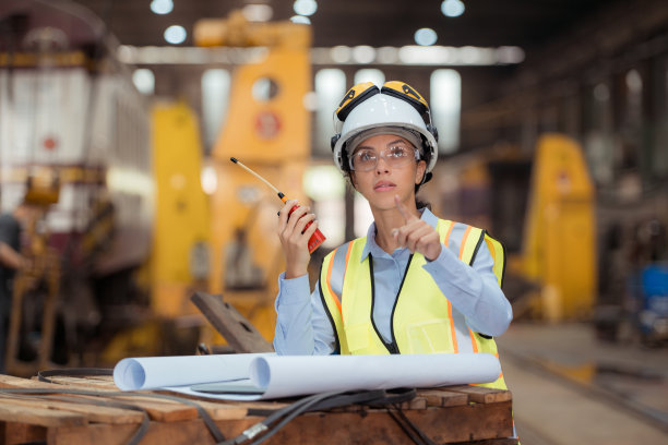 穿着安全背心和安全帽的铁路技术工人在火车维修站按图纸工作的照片图片下载