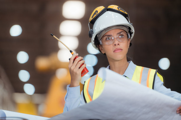 穿着安全背心和安全帽的铁路技术工人在火车维修站按图纸工作的照片图片下载