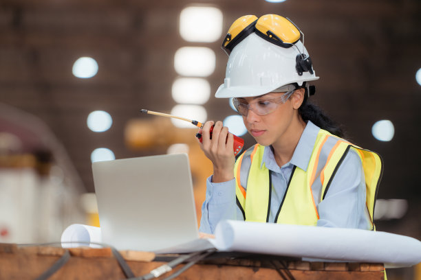 穿着安全背心和安全帽的铁路技术工人在火车维修站按图纸工作的照片图片下载