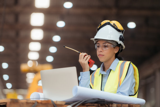 穿着安全背心和安全帽的铁路技术工人在火车维修站按图纸工作的照片图片下载