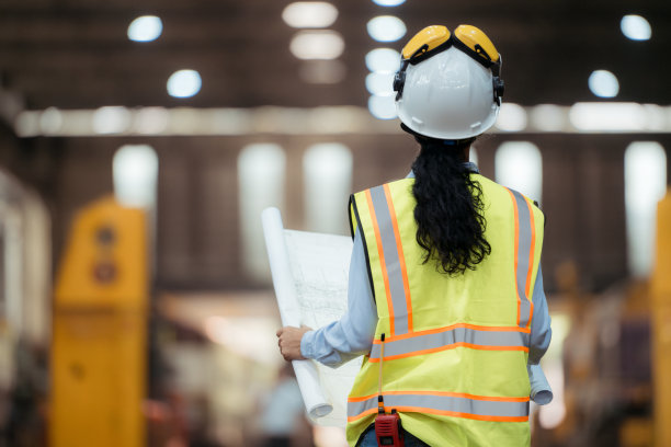 穿着安全背心和安全帽的铁路技术工人在火车维修站按图纸工作的照片图片下载
