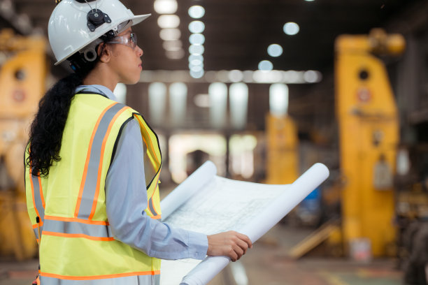 穿着安全背心和安全帽的铁路技术工人在火车维修站按图纸工作的照片图片下载