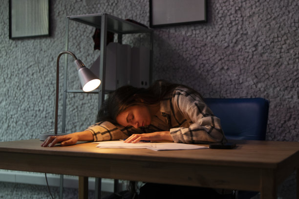 疲惫的年轻女工在办公室的办公桌前睡着了图片下载