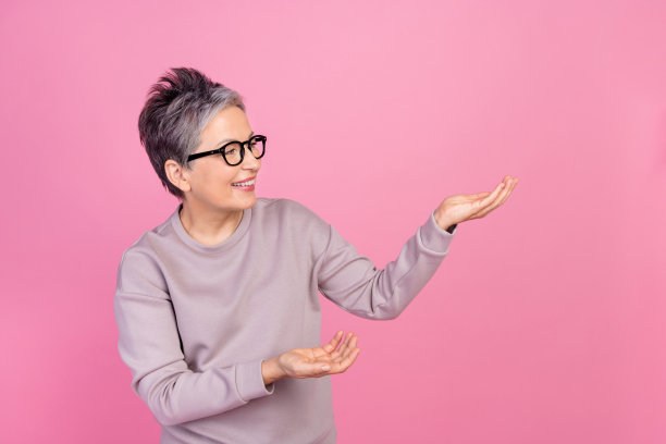 照片看起来退休妇女在时尚的运动衫在办公室商务沙发展示新课程孤立的粉红色背景图片下载