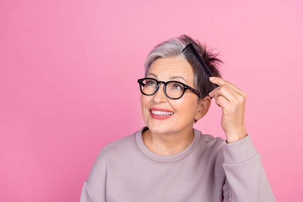 照片正面的可爱漂亮的女人拿着梳子梳头，看空空间沙龙特别主张孤立在粉红色的背景图片下载