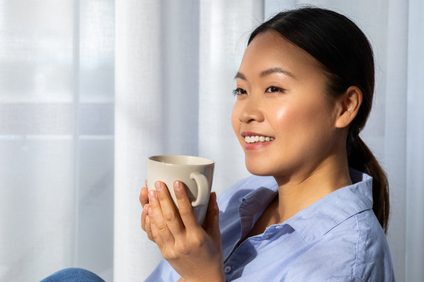 放松的年轻亚洲女人在家里享受咖啡图片下载