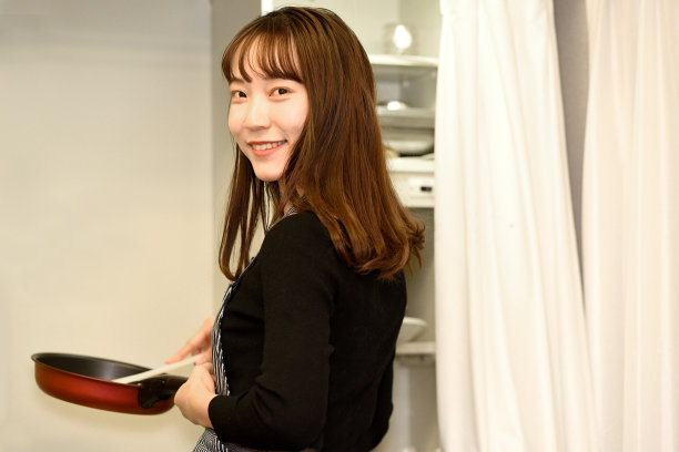 年轻的亚洲妇女系着围裙在室内做饭图片下载