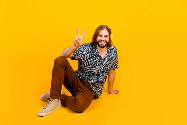 全身照片的酷时髦的家伙穿印花衬衫显示v字听音乐孤立的黄色背景图片下载