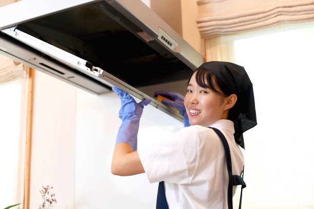 一位年轻的亚洲女管家正在清洁和检查厨房里的抽油烟机。图片下载