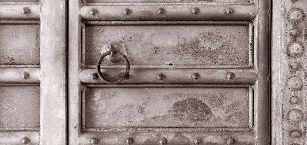 一扇有质感的、质朴的、灰褐色的、饱经风霜的古董门的横向照片，门上有复杂的设计和一个圆形的门环，门上有一个老式的框架图片下载