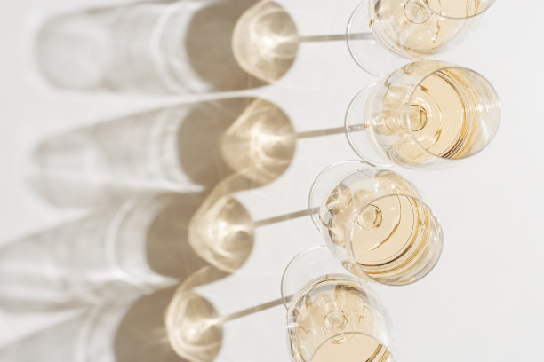 全白酒杯最小的风格以上视图。假日美学静物照片，俯视图闪闪发光的水晶酒杯在自然的阳光下，硬阴影，简单的酒精饮料背景，copyspace图片下载