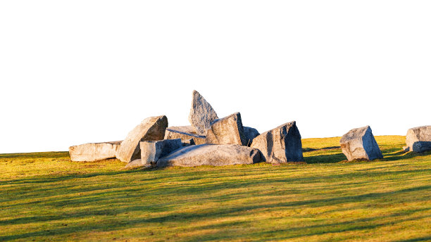 在夕阳照射下的草坪上，巨石的构图与背景分开，形成长长的阴影。图片下载