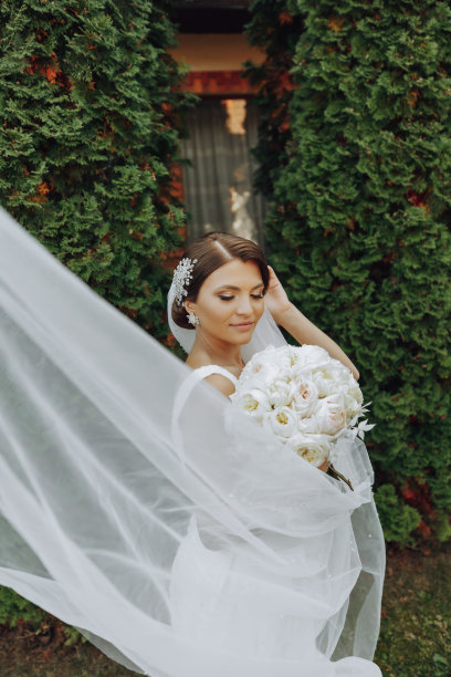 新娘手里捧着一束美丽的白色结婚花。公园里的户外照片。时尚的新娘。精致的妆图片下载