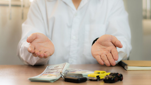 特写:手给车钥匙和钱，用于贷款、信用金融和租赁。汽车贷款概念，汽车换现金概念，金融概念。买卖新车或二手车。车钥匙在桌子上。图片下载